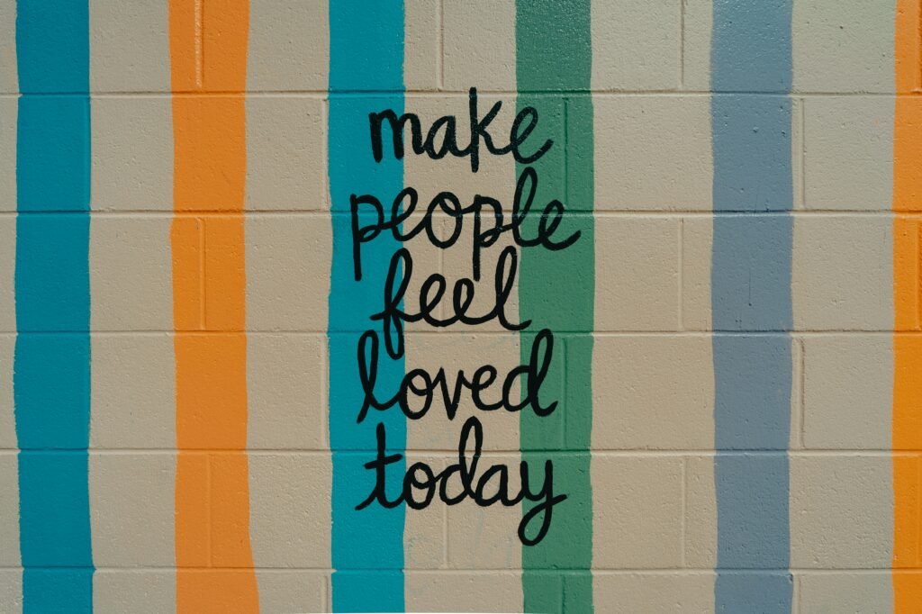 Wall mural with colorful stripes reading “make people feel loved today.”